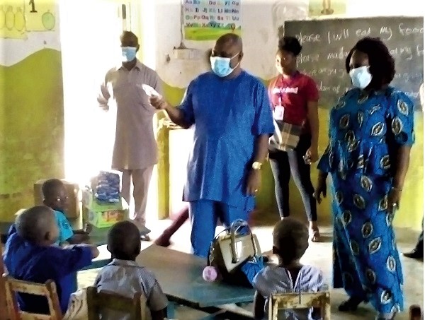 Mr Samuel Kwame Agyekum (middle), DCE for Asuogyaman, educating the children on the use of hand sanitiser   
